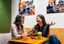 Cómo saber si una persona miente: señales que no son fiables Dos personas conversan frente a frente en una cafetería, ilustración de diálogo y escucha