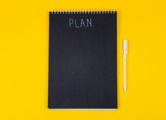 Cuaderno con la palabra plan y marcador sobre una mesa amarilla