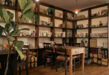 Estanterías de libros y mesa de lectura en una estancia iluminada.