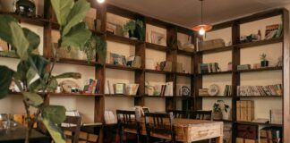 Estanterías de libros y mesa de lectura en una estancia iluminada.