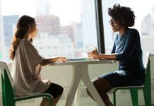 Dos mujeres conversan sentadas frente a una mesa