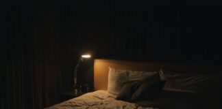 Lámpara de noche encendida junto a la cama, imagen ilustrativa de hábitos de sueño