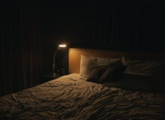 Lámpara de noche encendida junto a la cama, imagen ilustrativa de hábitos de sueño